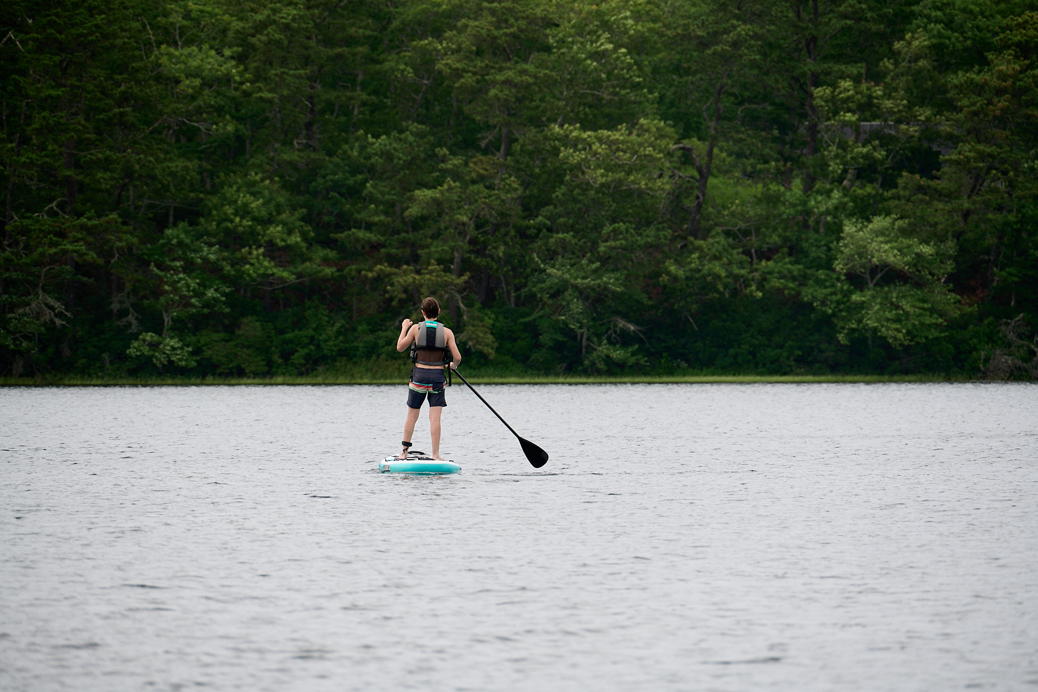 A teennager paddles a stand up paddle board